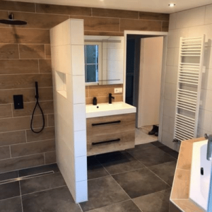 Badkamer betegeld met donkere vloer betonlook tegel gecombineerd met bruine houtlook tegels.