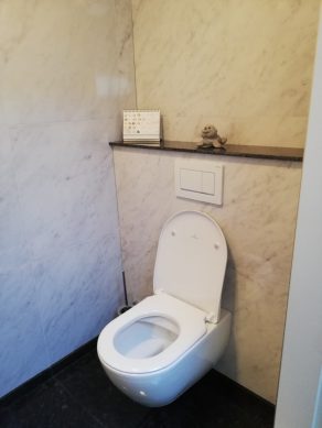 Hoogglans vloertegel 60×60 cm Marmerlook Bianco Carrara C108 op het toilet geplaatst.
