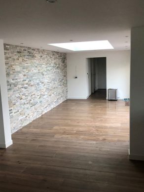 Houtlook tegel 30x150 cm N14 Bruin met noesten op de vloer in de woonkamer geleged