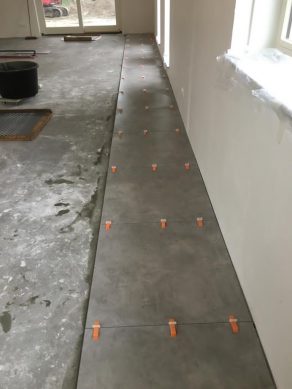Vloertegel 60×60 cm Betonlook Ariel Antraciet NR20 tijdens het legproces.